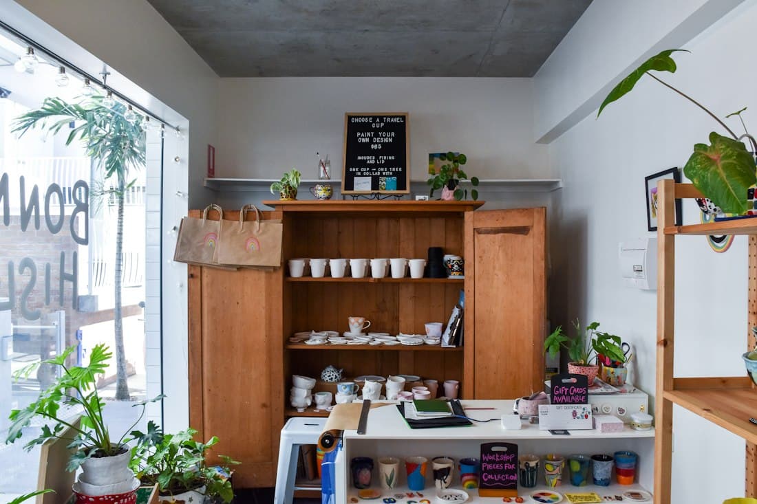 A small craft shop with ceramics on wooden shelves